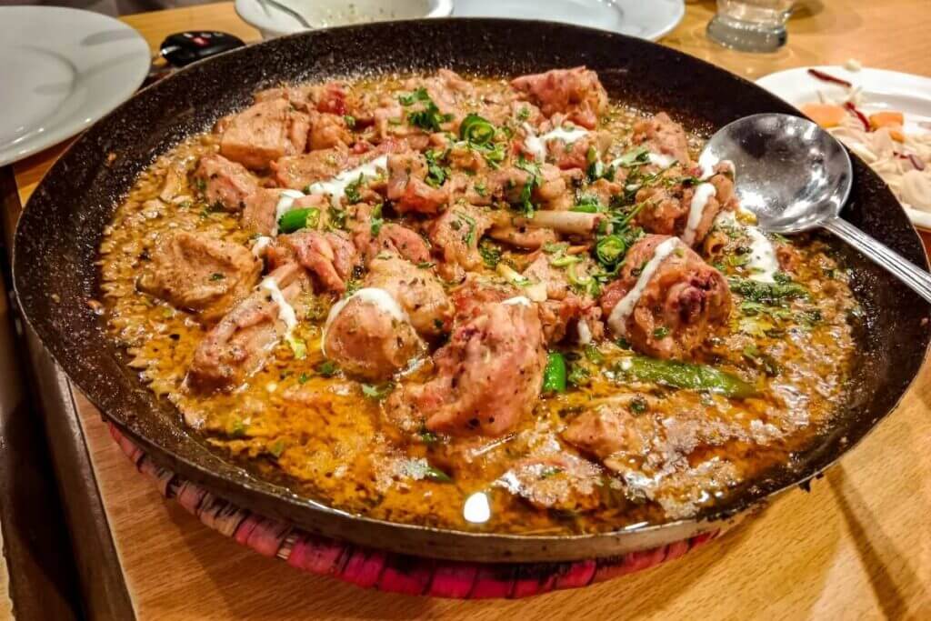 A delicious homemade chicken karahi or stew served in a traditional pan, representing a healthy home-cooked meal for a budget diet.