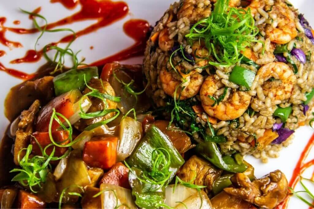 Healthy shrimp and vegetable stir-fry served with a side of nutritious brown rice on a white plate.